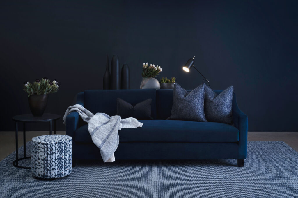 Dark blue sofa with grey rug and scatter cushions for high-end bachelor pads