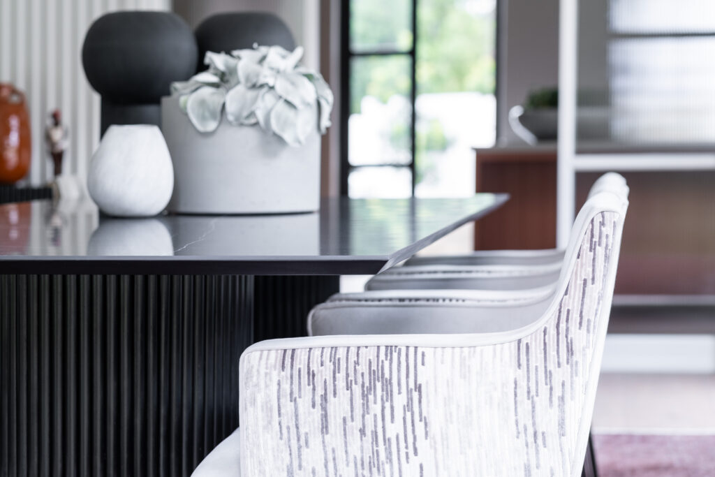 Black dining room table with comfortable white chairs and black and white table accessories