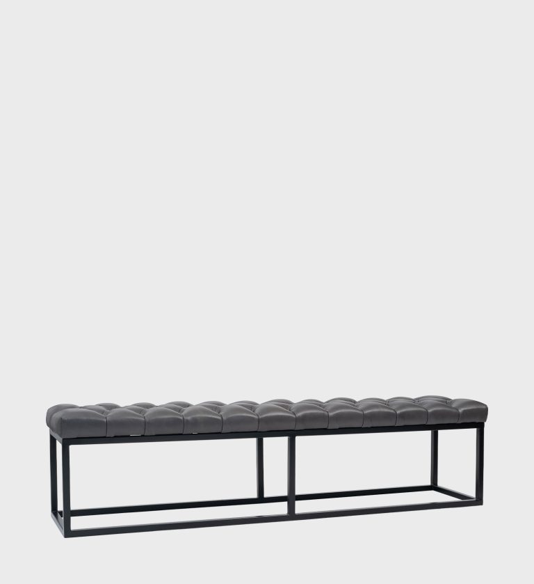 The Kelly Ottoman Steel Base blends industrial precision with refined comfort. Its tufted dark‑grey seat rests on a sleek black steel frame,