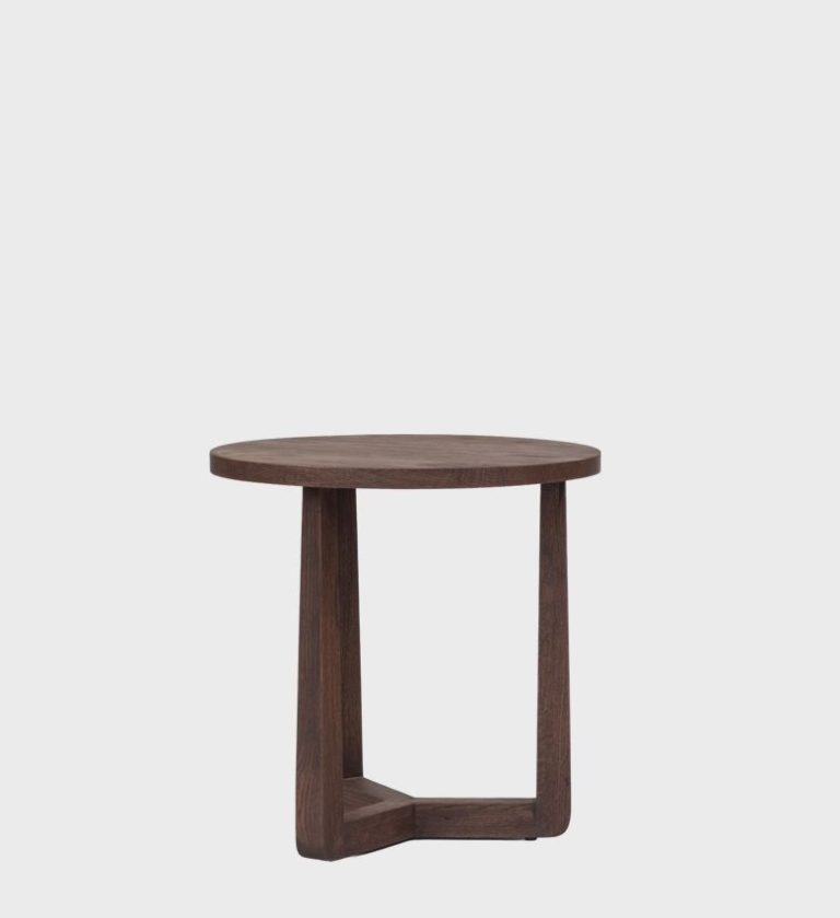 The Afton Side Table Small Walnut is a compact expression of modern craftsmanship. Its circular walnut top rests on three subtly tapered legs joined by a triangular base, creating a sculptural yet stable form.
