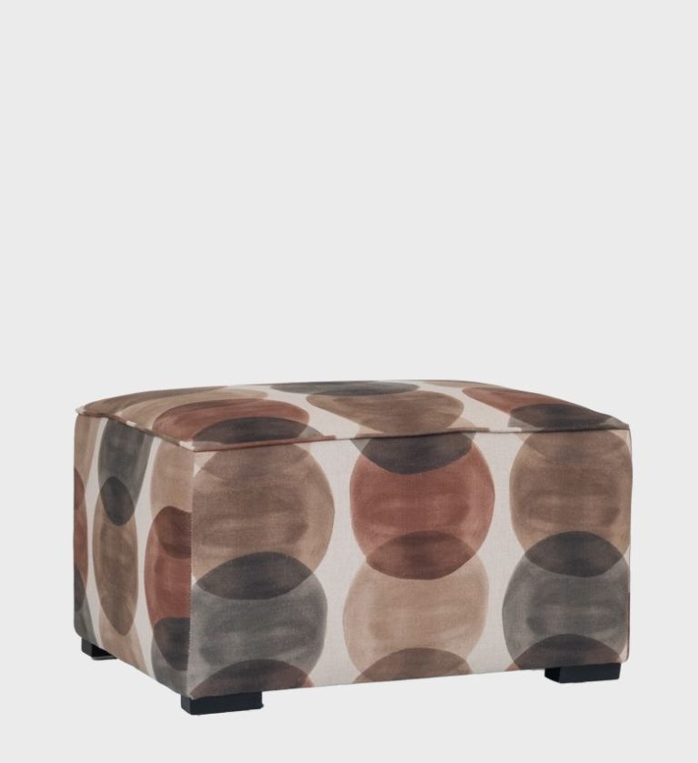The Cube Ottoman introduces playful geometry to modern interiors with its bold circular pattern in earthy tones of brown, beige, and muted red.