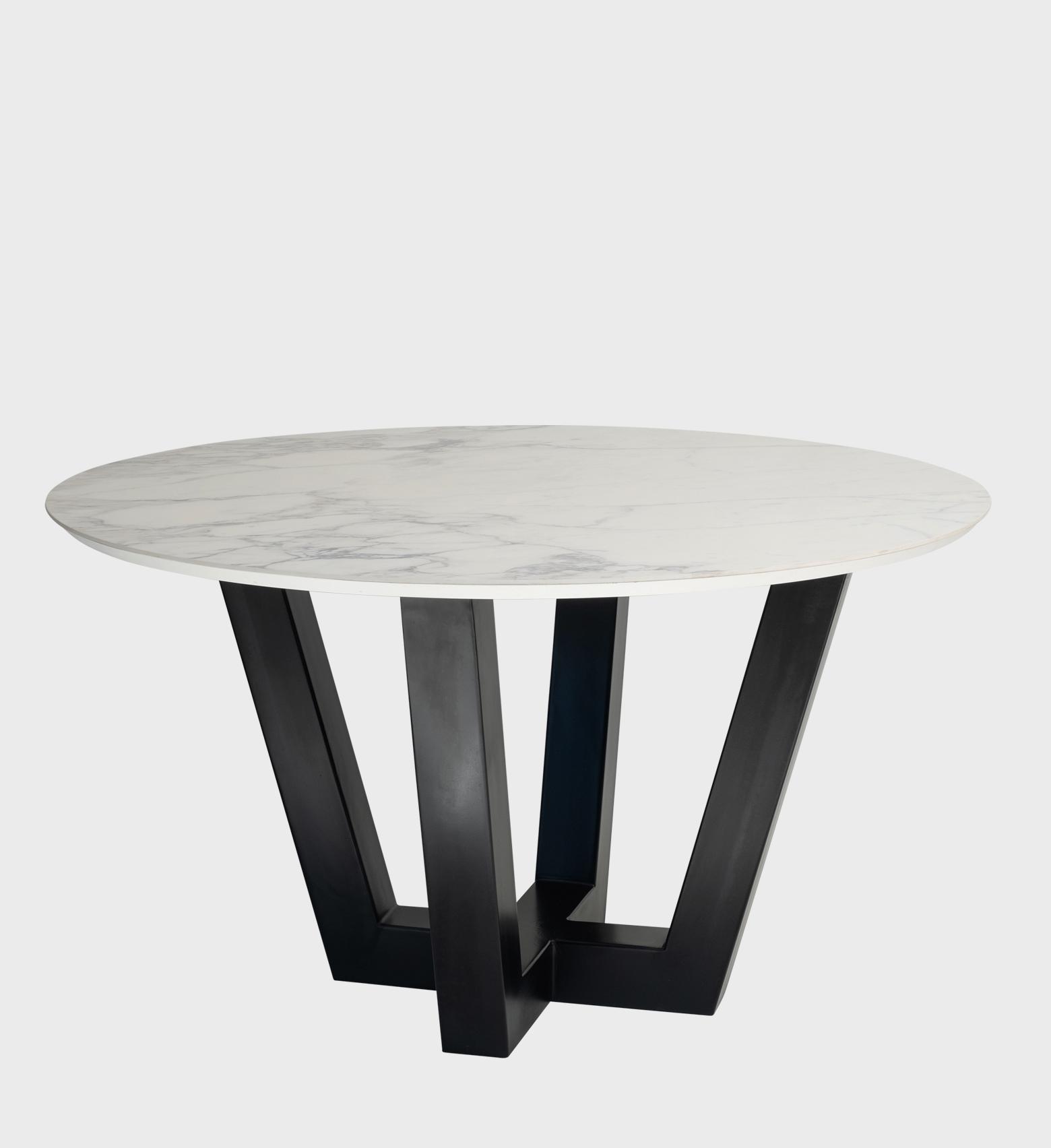 The Bellissima Table is a striking fusion of elegance and modern geometry. Its round marble‑effect top, with subtle gray veining, rests on a sculptural black base composed of angular intersecting legs.