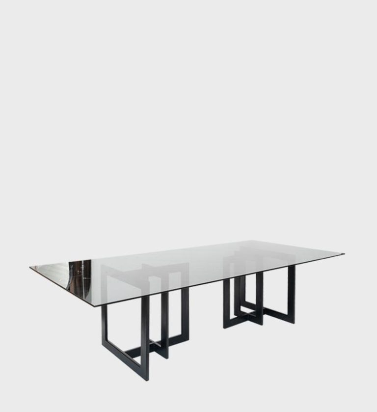 The Zandi Dining Table is a striking example of modern minimalism and structural artistry. Its expansive rectangular glass top rests on a geometric metal base composed of interlocking rectangular frames in a deep black finish.