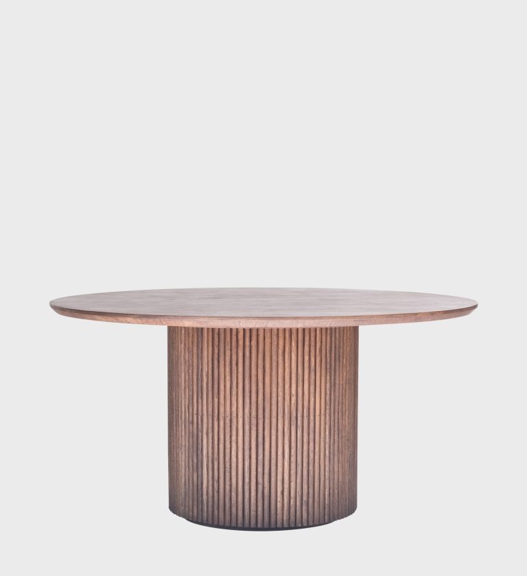 The Luvuvhu Round Wooden Dining Table Walnut captures the essence of organic warmth and sculptural balance. Its circular top, crafted from richly grained walnut, rests on a cylindrical base adorned with vertical fluting that adds rhythm and texture.