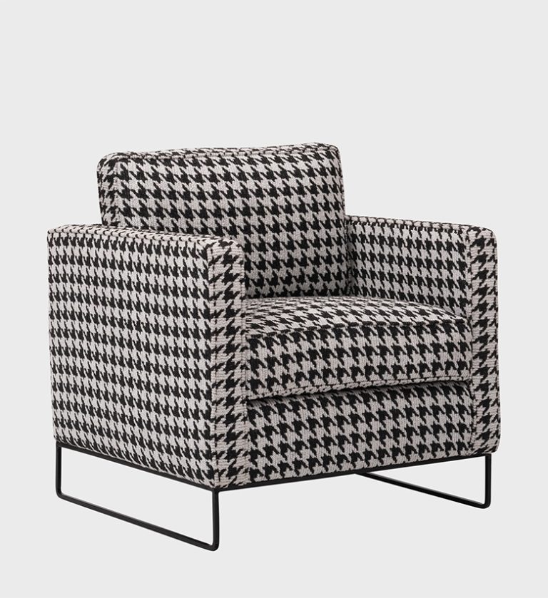 The Manhattan Armchair is a bold fusion of classic pattern and modern form. Upholstered in a striking black‑and‑white houndstooth fabric