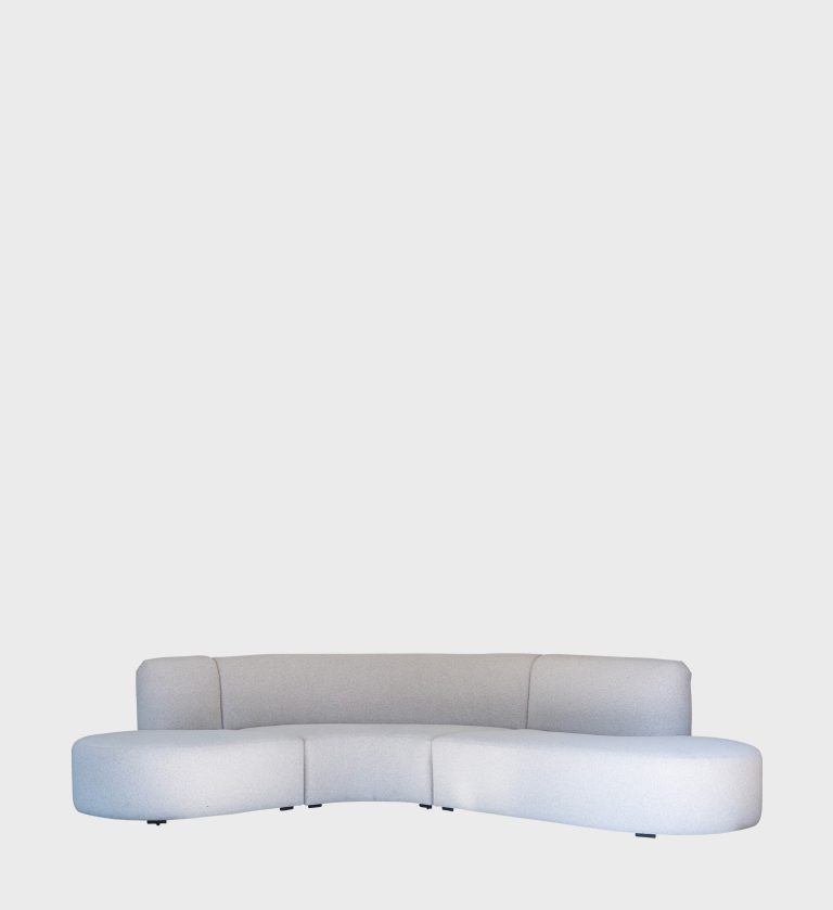 Curved cream boucle sofa in a sunlit living room with a gold floor lamp, wooden coffee table, and natural woven rug — modern minimalist interior by JVB Furniture Collection