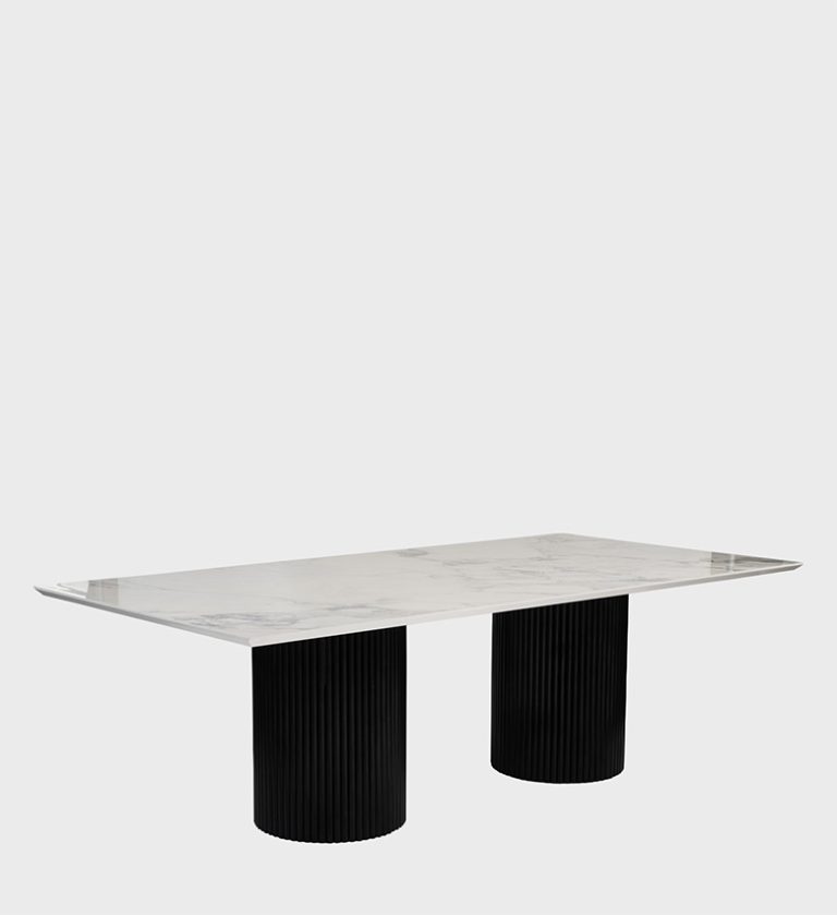 The Venice Dining Table is a masterclass in architectural elegance and material harmony. Its expansive rectangular top, finished in deep stone with subtle veining, rests on two cylindrical fluted bases that introduce rhythm and sculptural balance.