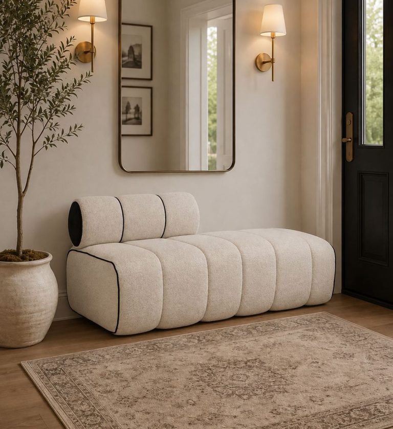 The Milan Ottoman embodies modern sophistication with its sculptural form and clean geometry. Upholstered in a soft off‑white fabric and accented by bold black piping