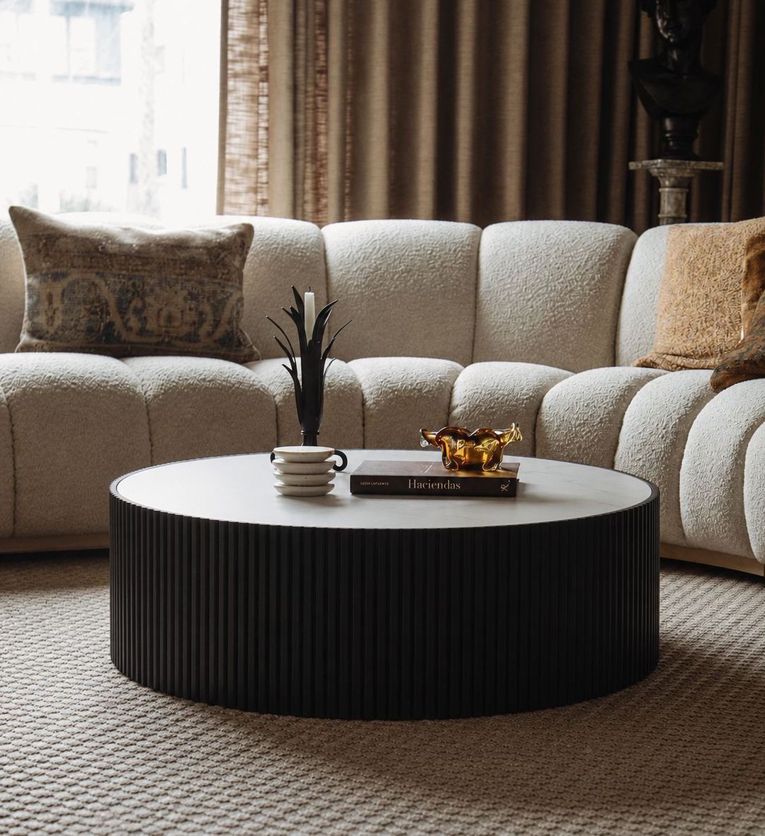 The Venice Coffee Table Ebony is a stunning centerpiece that merges sculptural texture with refined simplicity. Its round silhouette features a vertically fluted base in deep ebony, adding rhythmic depth and architectural character.
