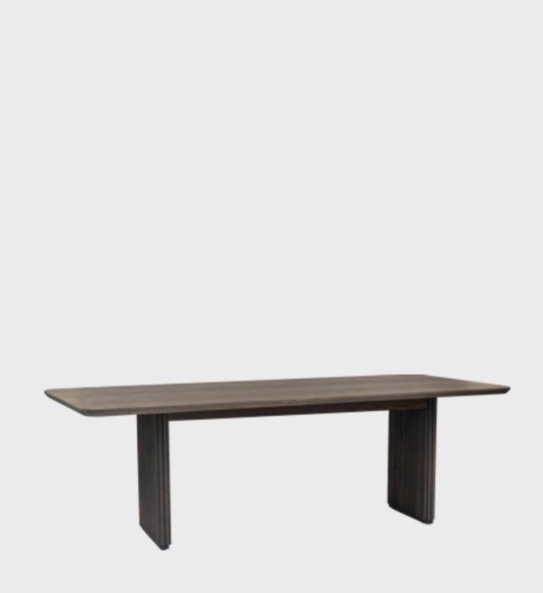 The Linga Dining Table is a refined example of minimalist craftsmanship. Its elongated rectangular top features softly rounded edges and a smooth, dark wood finish that highlights natural grain patterns.