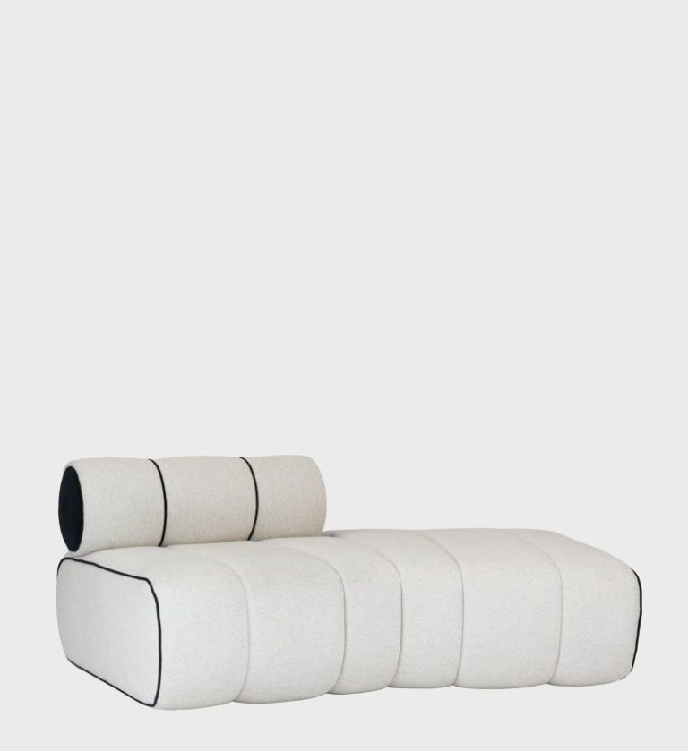 The Milan Ottoman embodies modern sophistication with its sculptural form and clean geometry. Upholstered in a soft off‑white fabric and accented by bold black piping