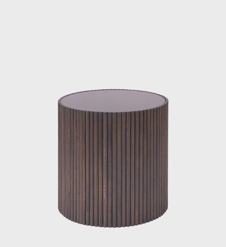 The Fluted Side Table Storm embodies modern sophistication through its sculptural simplicity. Crafted with a cylindrical form, it features vertical wooden fluting that adds rhythmic texture and depth